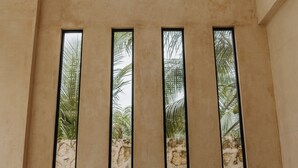 A room with a high ceiling, large windows, and a stone wall. - Ik Casa Del Viento  (Chetumal)