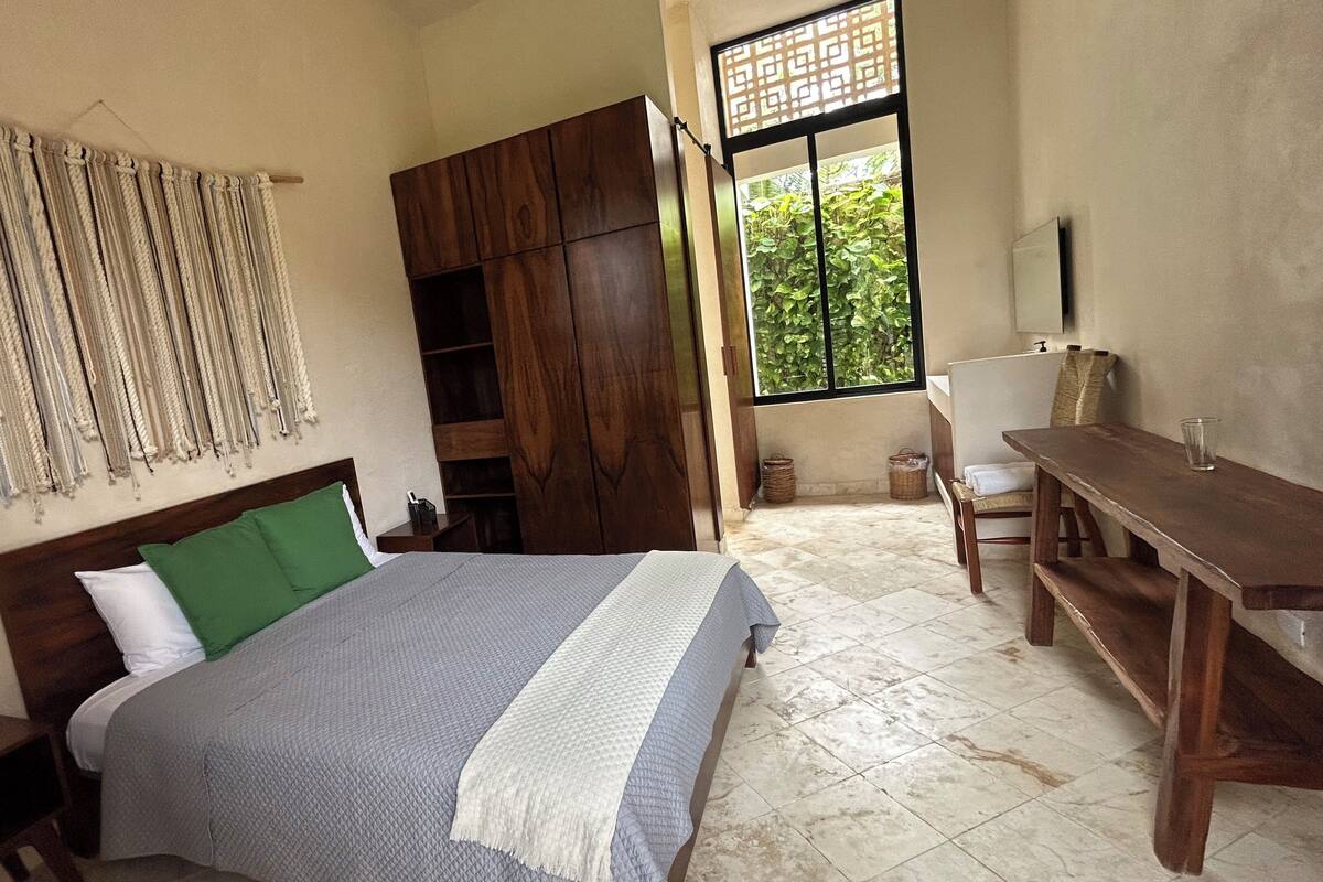 Ein Schlafzimmer mit Bett, Holzschrank, Schreibtisch und Stuhl.