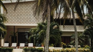 A wooden dock leading to a building with a thatched roof, surrounded by palm trees and a well-maintained lawn. - Ik Casa Del Viento  (Chetumal)