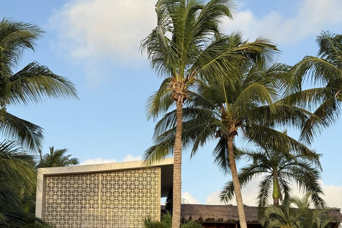 Ein Resort mit Pool, Palmen und einem Gebäude mit einer rasterförmigen Fassade.