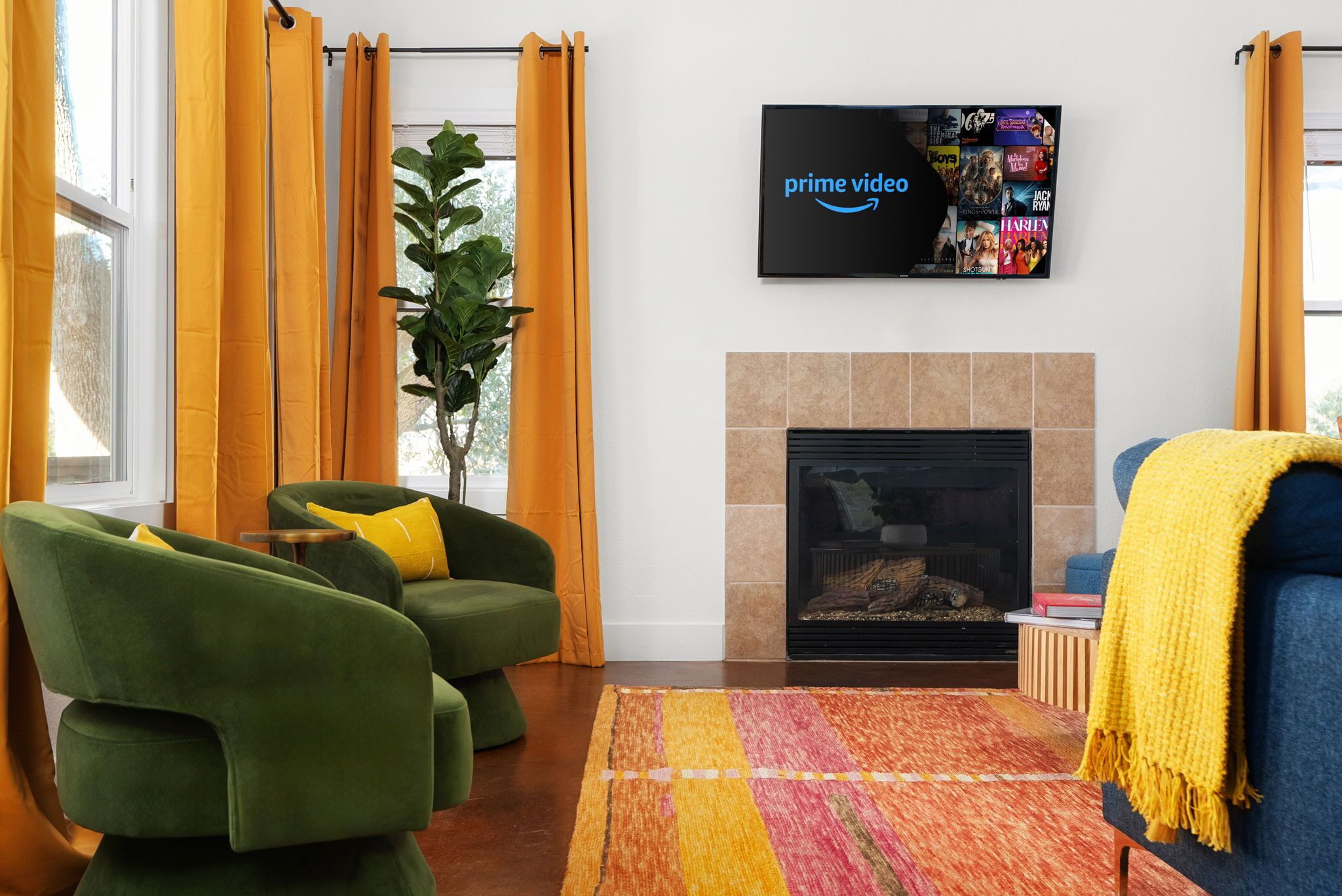 A living room with green armchairs, a fireplace, and a flat-screen TV displaying Prime Video.