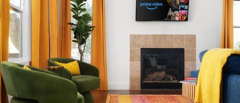 A living room with green armchairs, a fireplace, and a flat-screen TV displaying Prime Video.