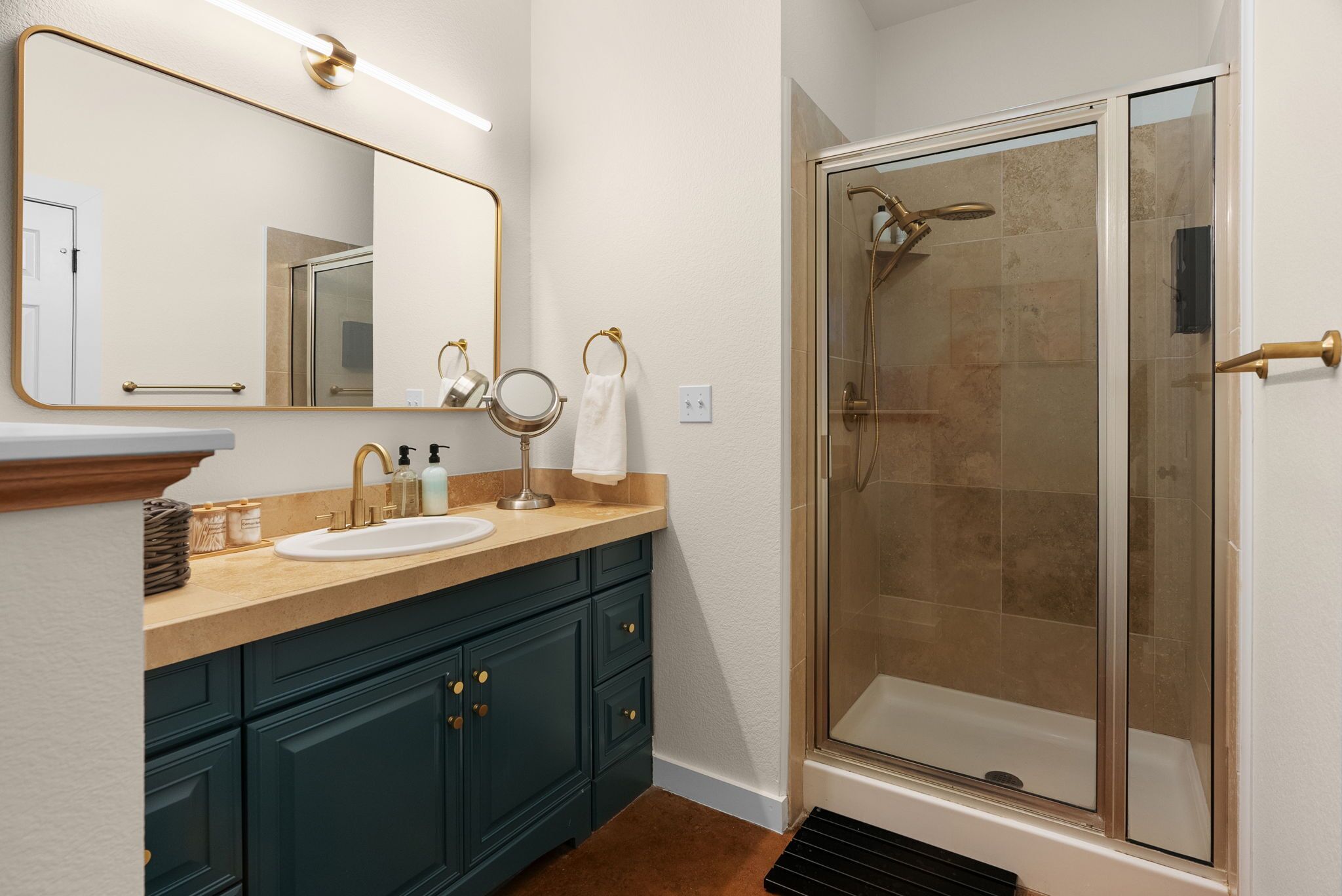 A bathroom with a sink, mirror, and shower.