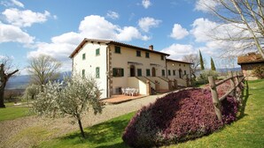A two-story building with a patio and outdoor seating area. - Farmhouse in Tuscany With Pool and Valley Views (Poppi)