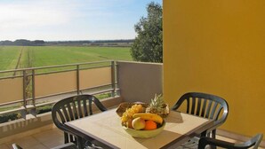 A balcony with a table, chairs, and a bowl of fruit. - Residence with pool in Luni Mare (Luni)