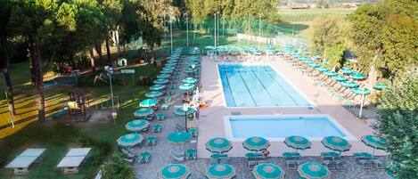 Ein Poolbereich mit mehreren Schwimmbecken, Liegestühlen und Sonnenschirmen.