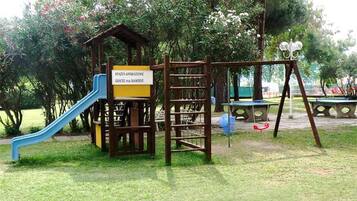 Un parque infantil con tobogán, estructura de escalada y un cartel que indica 'Parque infantil'.