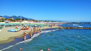 A crowded beach with people swimming and sunbathing, umbrellas, and boats. - Residence with pool in Luni Mare (Luni)