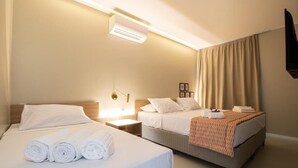 Een hotelkamer met twee bedden, een nachtkastje, een airconditioner en een televisie.