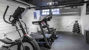 Een fitnessruimte met hometrainers, loopbanden en een dumbbellsrek.