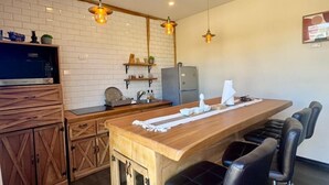 Une cuisine moderne dotée d’un îlot central en bois, de tabourets de bar, de luminaires suspendus et d’un mur de fond en briques.