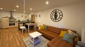 Una sala moderna con un sofá marrón, una mesa de comedor y una cocina al fondo.