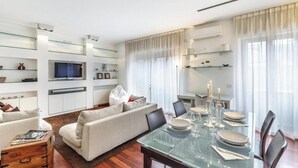 A modern living room with a glass dining table, sofa, and built-in shelving. - Modern Apartment in Porta Nuova, Milan

 (Milano)
