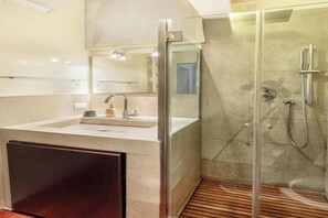 A modern bathroom with a glass-enclosed shower, a sink with a mirror, and a wooden floor. - Modern Apartment in Porta Nuova, Milan

 (Milano)