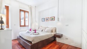 A bedroom with a wooden bed, white walls, and a window with curtains. - Modern Apartment in Porta Nuova, Milan

 (Milano)