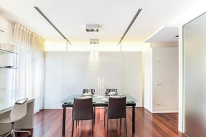 A modern dining area with a glass table, two chairs, and a white cabinet. - Modern Apartment in Porta Nuova, Milan

 (Milano)