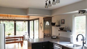 Una cocina moderna con armarios oscuros, una mesa de comedor de madera e iluminación colgante.