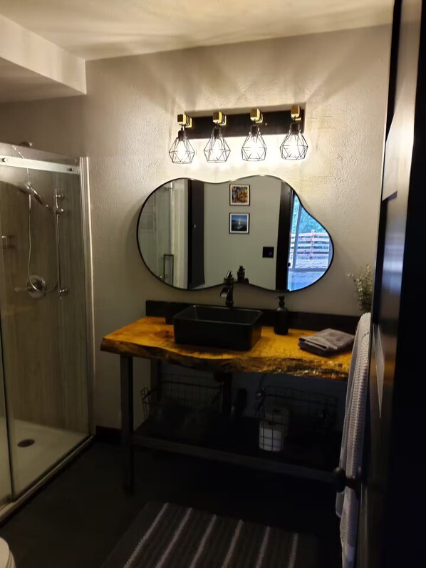 A bathroom with a large mirror, a sink, and a shower.