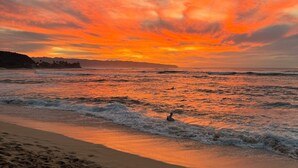 Une plage avec des vagues et un coucher de soleil.