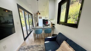 Un intérieur moderne avec un canapé bleu, un coin cuisine et de grandes fenêtres.