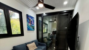 Un salon moderne avec un canapé bleu, une table à manger et un ventilateur de plafond.