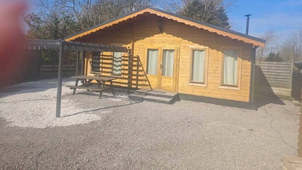 Une cabane en bois avec un toit en pente, une véranda et une allée gravillonnée.