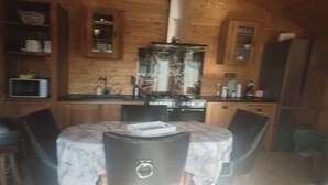 L’intérieur d’une cabane en bois comprend une table à manger, des chaises, un coin cuisine et des placards intégrés.