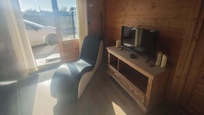L’intérieur d’une cabane en bois comprend un fauteuil inclinable, un téléviseur posé sur un meuble en bois et un panneau indiquant la sortie de secours en cas d’incendie.