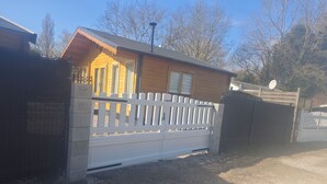 Une cabane en bois avec une clôture en piquets blancs, une allée en gravier et une antenne parabolique.