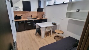 A compact kitchen with a microwave, sink, and stove. There is a small dining table with chairs.