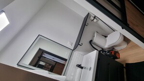 A modern bathroom with a white toilet, a towel rack, and a mirror.