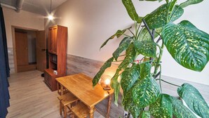 A room with a wooden dining table, a bench, a cabinet, and a large potted plant. - Tokyo Vibes Hostel with more privacy (Self Check in) (Vilnius)