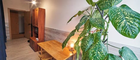 A room with a wooden dining table, a bench, a cabinet, and a large potted plant.