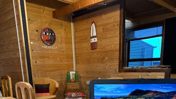 A wooden interior with a laptop displaying a scenic map, a plate with a dessert, and a milk glass.