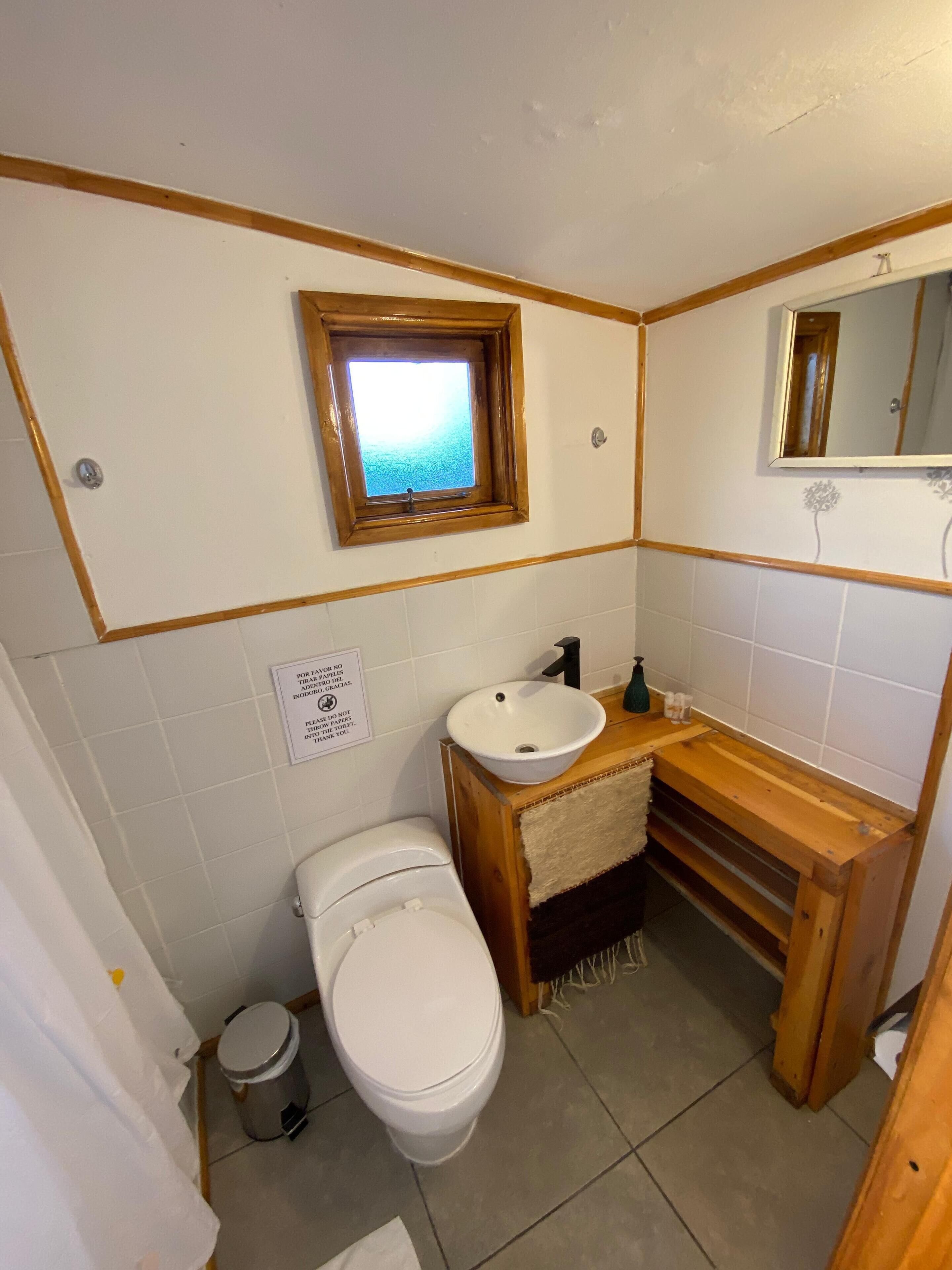 A small bathroom with a toilet, sink, and window.