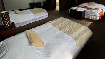 Habitación de hotel con dos camas individuales, cabecera de madera, espejo, cómoda de madera y cortina colorida.