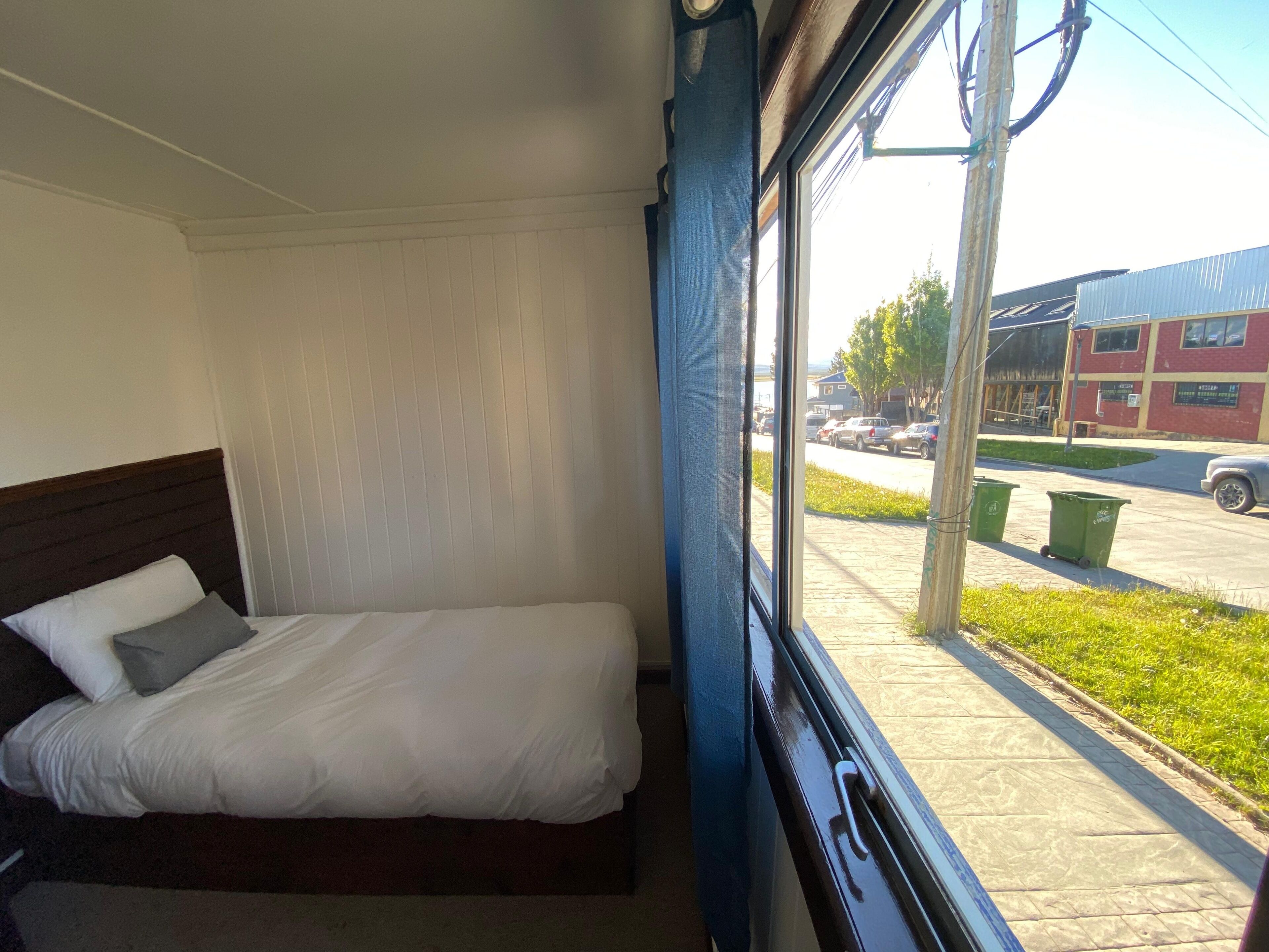 Une chambre d’hôtel avec un lit et une fenêtre donnant sur la rue et les immeubles.