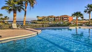 A resort pool with palm trees and a building in the background. - Hole-in-One Vista! (Laguna Vista)