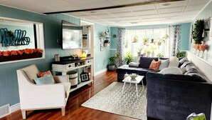 A living room with a sofa, armchair, and coffee table. There are plants and decorative items on shelves and the wall. - Stylish and Spacious 3 bedroom home located 3.4 mi from downtown Erie, PA (Erie)