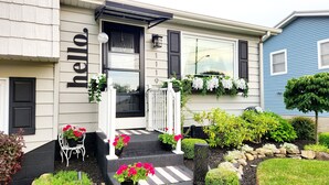 A two-story house with a black door and white steps leading to the front door. There are potted plants and flowers on the steps, and a mailbox on the front porch. - Stylish and Spacious 3 bedroom home located 3.4 mi from downtown Erie, PA (Erie)
