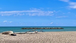 A beach with a rocky outcrop in the distance, a picnic table, and a clear blue sky. - Stylish and Spacious 3 bedroom home located 3.4 mi from downtown Erie, PA (Erie)