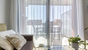 A living room with a sofa, a glass coffee table, and a potted plant. - Coastal Getaway in Empuriabrava for 4 (Castello d'Empuries)