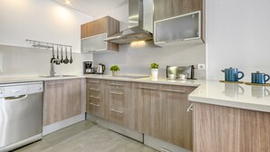 A modern kitchen with wooden cabinets, stainless steel appliances, and a built-in microwave. - Coastal Getaway in Empuriabrava for 4 (Castello d'Empuries)