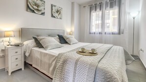 A neatly arranged bedroom with a bed, bedside tables, and a lamp. - Coastal Getaway in Empuriabrava for 4 (Castello d'Empuries)