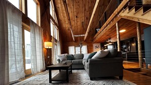 A spacious living area with a large sofa set, a coffee table, and a patterned rug. - Cozy Chalet – Mtn View+ Hot Tub+ Hike+ Santa's Vil (Lancaster)