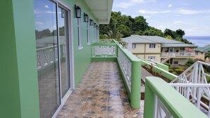 A green building with a tiled balcony and a view of the ocean. - Sea and Summit Suite #1 (Castle Comfort)