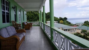 A balcony with wicker furniture and a view of the sea. - Sea and Summit Villa (Roseau)