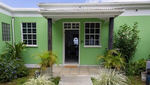 A house with a green exterior, a front door, and a small porch area. - Sea and Summit Villa (Roseau)