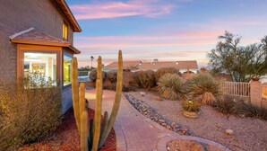 A residential property with a paved pathway, cacti, and a brick house.