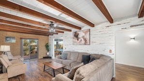A spacious living room with a sectional sofa, a coffee table, and a ceiling fan.